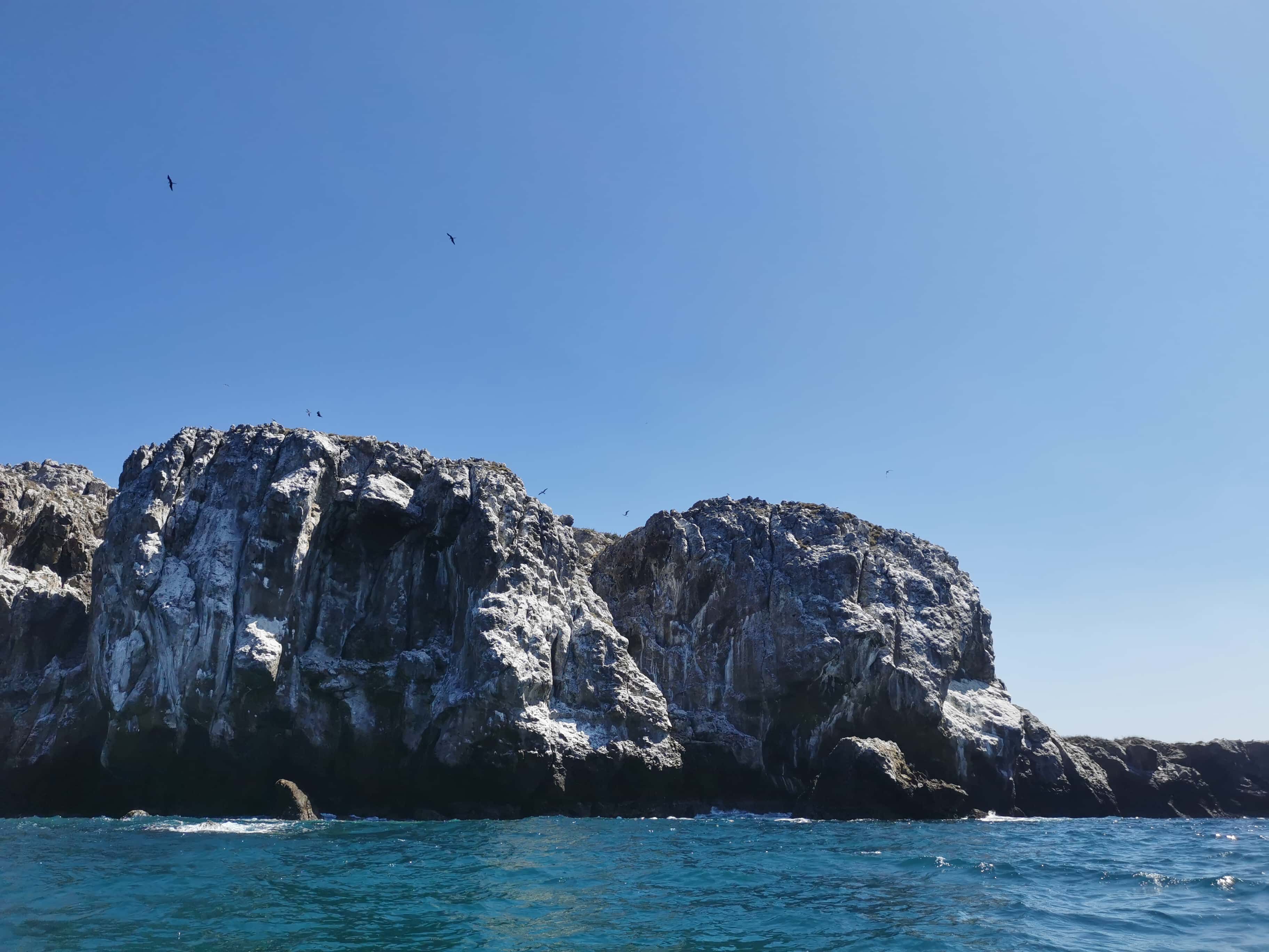 Acantilados volcánicos de las Islas Marietas con aves marinas volando sobre ellos